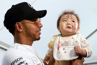 El piloto Lewis Hamilton (Mercedes) carga a un bebé durante un encuentro con aficionados de la Fórmula Uno en la antesala del Gran Premio de Japón en Suzuka.