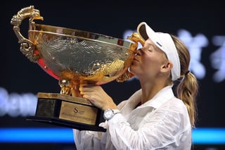 La danesa Caroline Wozniacki besa el trofeo que la acredita como campeona del Abierto de China.