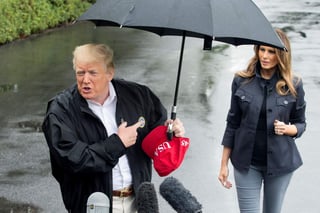 Trump sostenía un paraguas para protegerse del clima, pero en un momento en que se acercó a los periodistas, no lo compartió con su esposa. (EFE)