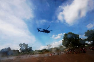 Un helicóptero de la policía mexicana sobrevuela a los integrantes de la segunda caravana de migrantes, en su mayoría hondureños, mientras cruzan a pie el río Suchiate por una parte que no es muy profunda y que separa a Guatemala de México, en un nuevo intento por continuar su travesía hacia Estados Unidos, hoy, lunes 29 de octubre de 2018, en Tecún Umán (Guatemala). (EFE)