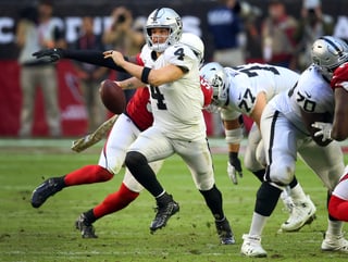 El quarterback de los Raiders de Oakland, Derek Carr (4), escapa de la presión mientras busca un wide receiver contra los Cardinals de Arizona, durante la primera mitad de un juego de la NFL.