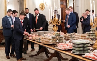 Los miembros del equipo de futbol americano Clemson Tigers, campeones nacionales universitarios, se preparan para cenar comida rápida servida por el presidente de los Estados Unidos, Donald J. Trump.