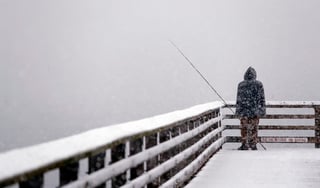 Frío. Hershel Odle mira al horizonte, completamente blanco por una tormenta de nieve, mientras pesca en un muelle en Seattle.