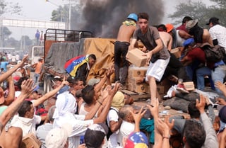 Desesperados. Venezolanos intentan rescatar parte de la ayuda humanitaria que se encuentra en un camión que fue quemado por miembros de la Guardia Nacional en la frontera con Colombia. La crisis también se agudiza diplomáticamente.