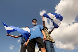 Tres jóvenes ondean banderas de Nicaragua durante una protesta para exigir que el gobierno libere a los manifestantes detenidos. (AP)