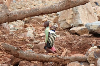 Un niño con un bebé en su espalda caminó ayer a través de escombros después del ciclón Idai en Ngangu, Chimanimani, Zimbabue. (EFE) 