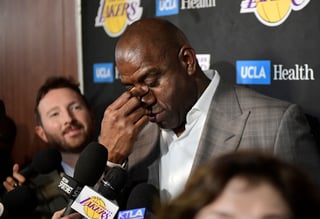 Earvin 'Magic' Johnson se limpia los ojos mientras informa a reporteros sobre su renuncia a la presidencia de los Lakers.