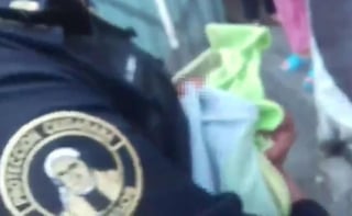 En un video que circula en redes sociales se observa que un policía capitalino carga y tapa a la bebé. (ESPECIAL) 

