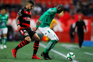 El delantero de Xolos, Gustavo Bou, disputa una pelota contra el zaguero de León, Andrés Mosquera, en la ida de los cuartos de final.