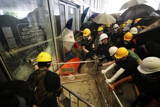 Centenares de personas se congregaron ante las puertas del Parlamento hongkonés y, en un momento dado, un grupo de ellos rompió las barreras de acero que las protegían y las usaron como ariete para destruir los cristales y tratar de acceder al interior. (EFE)