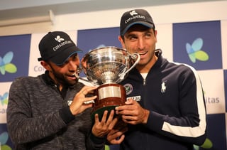 Juan Sebastián Cabal (i) y Robert Farah muerden el trofeo de Wimbledon. (ARCHIVO)