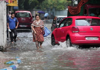 Una mujer camina por una calle inundada en Calcuta, India, por las lluvias del monzón el pasado sábado. (EFE)