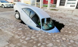 El conductor de un vehículo Ford quedó atrapado por varios minutos, cuando su unidad cayó a un enorme socavón que se abrió a su paso, sobre la calle Luis Nishisawa, de la ampliación del fraccionamiento Villa Verde, en la ciudad de Mazatlán. (ESPECIAL)
