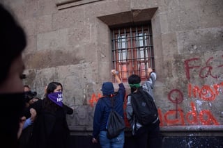 Un grupo de manifestantes realizó pintas en la fachada principal de Palacio Nacional con pintura en aerosol de diferentes colores, además prendieron velas y pegaron un par de calcomanías con consignas contra la violencia de género. (NOTIMEX)