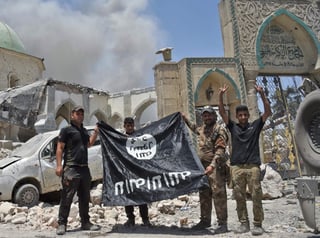 Militares iraquíes sostienen una bandera de ISIS en Mosul.