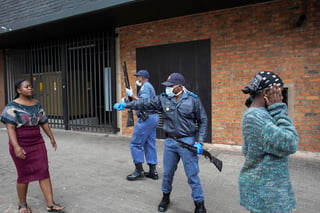 Policía de Sudáfrica da indicaciones sobre distanciamiento social a un grupo de mujeres. (EFE) 