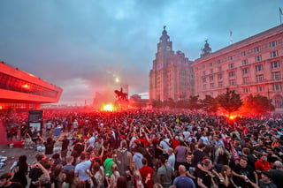 Fanáticos del Liverpool encienden bengalas frente al Liver Building, el viernes, para celebrar el título del equipo. (AP)