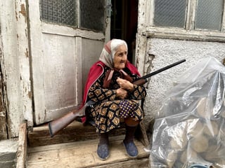 Una anciana con su escopeta en la puerta de su casa en Stepanakert, la capital del enclave separatista de Nagorno Karabaj, disputada por Azerbaiyán y Armenia. (EFE) 