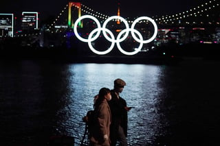 Una pareja pasa cerca de los anillos olímpicos que flotan en el distrito de Odaiba en Tokio, Japón. (AP)