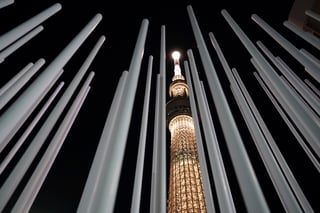 El Tokyo Skytree, edificio más alto de Japón, iluminado con el color de la antorcha olímpica para marcar 100 días hasta el inicio del relevo. (AP)