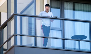 Novak Djokovic desde el balcón de su habitación, donde pasa la cuarentena previo al Abierto de Australia. (AP)