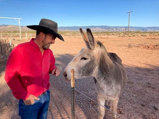 Couy Griffin, comisionado del condado Otero y creador de la organización Cowboys for Trump, cuida a su burro llamado Henry afuera de su casa en Tularosa, Nuevo México, el 12 de mayo de 2021. (AP Foto/Morgan Lee)