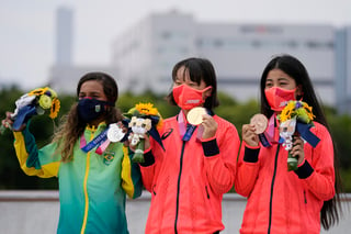 En el podio olímpico, tres chicas adolescentes - de 13, 13 y 16 años — con pesadas medallas de oro, plata y bronce en sus cuellos, celebraban la recompensa por ejecutar una serie de trucos con sus patinetas que muchos niños de su edad sólo pueden ver en Instagram. (AP)