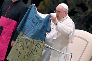 El papa Francisco muestra una bandera de Ucrania que fue enviada desde la localidad de Bucha durante la audiencia semanal en el Salón de Pablo VI en el Vaticano. (ARCHIVO)