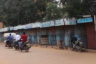 Tres motociclistas pasan delante de varias tiendas cerradas en Uagadugú, Burkina Faso. (EFE)