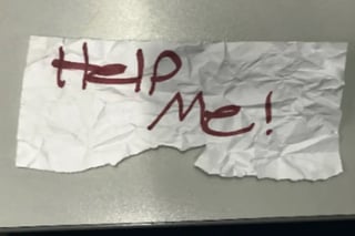 La niña escribió '¡Ayúdame!' en un pedazo de papel y lo sostuvo en alto. (AP)
