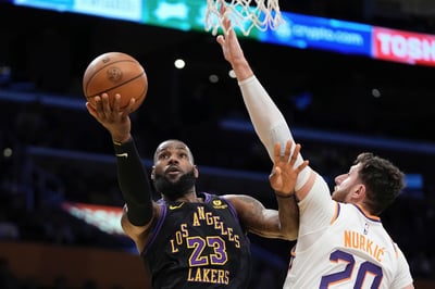 El alero de los Lakers de Los Ángeles LeBron James lanza el balón a la canasta mientras lo defiende el pívot de los Suns de Phoenix Jusuf Nurkic en el encuentro de la Copa de la NBA el martes 5 de diciembre del 2023. (AP Foto/Mark J. Terrill)