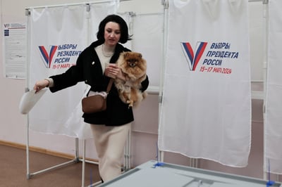 Una mujer sostiene su mascota a su salida de una cabina electoral durante unas elecciones presidenciales en la ciudad portuaria de Vladivostok, en el este de Moscú. (AP)