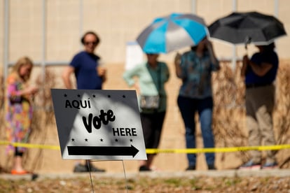Votantes usan sombrillas para cubrirse del sol mientras esperan formados en un centro de votación, el martes 5 de marzo de 2024, en San Antonio. (AP Foto/Eric Gay)
