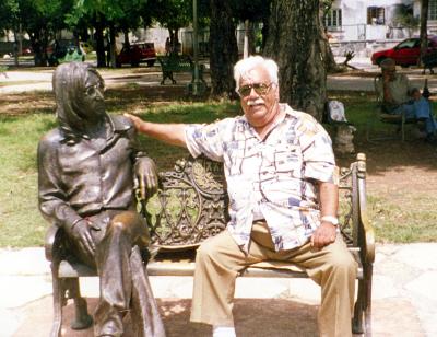 Jesús Valdivia González sentado junto a la estatua de John Lennon, en el parque Vedado de La Habana, Cuba.