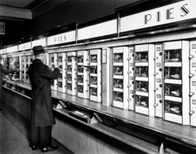 Un hombre obtiene una rebanada de pay  en este restaurante automático de Nueva York en el año  1830. Esta fotografía es una de las 250 que forman parte de una nueva exhibición en la biblioteca de Nueva York llamada 'Nueva York come fuera' y en la que se muestra el amor de los ciudadanos por la comida de la calle en los últimos 150 años.