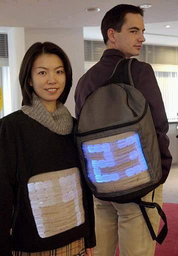 El staff japonés de la compañía TELECOM de Francia, muestra una chaqueta  y una mochila con pantalla de luz. Camisetas, chaquetas, vestidos de noche y otros artículos de moda que  utilizan esta nueva tecnología llamada 'Pantalla de fibra óptica' están ya disponibles en Francia.  La fibra óptica procesada es cosida entre la ropa para desplegar diseños llenos de colorido así como imágenes que se mueven.