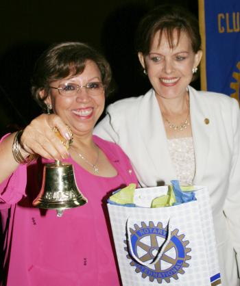 La señora Jose ávila de Ruiz recibe de manos de la esposa del gobernador rotario, Elisa Salazar de Morales, una campaña comio símbolo de la celebración de los 100 años de Rotary.