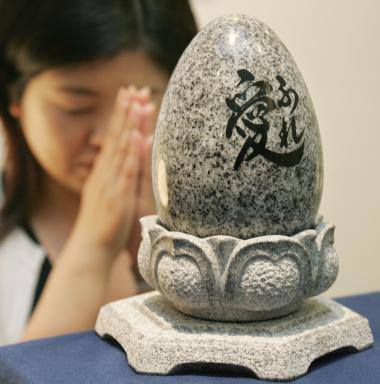 Una japonesa hace oración enfrente de un pequeño óvalo de granito donde descansan los restos de un difunto.
Las tumbas de granito tienen un costo de 1611 dólares aproximadamente.