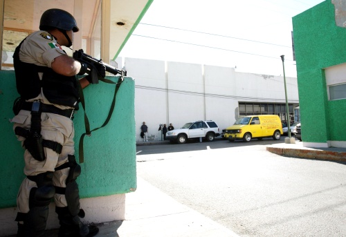 Un guardia del penal de Ciudad Juarez vigila el traslado a un hospital de reclusos heridos.