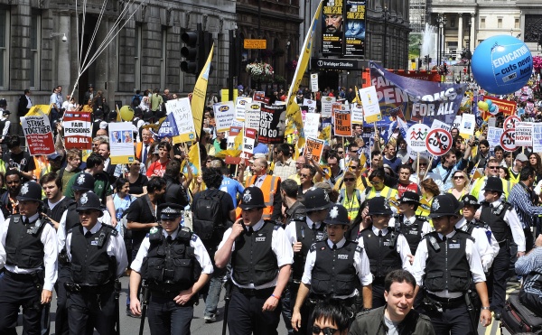 Policías miran la marcha de activistas del Sindicato de Servicios Públicos y Comerciales que pasan cerca de las puertas del Parlamento en Londres