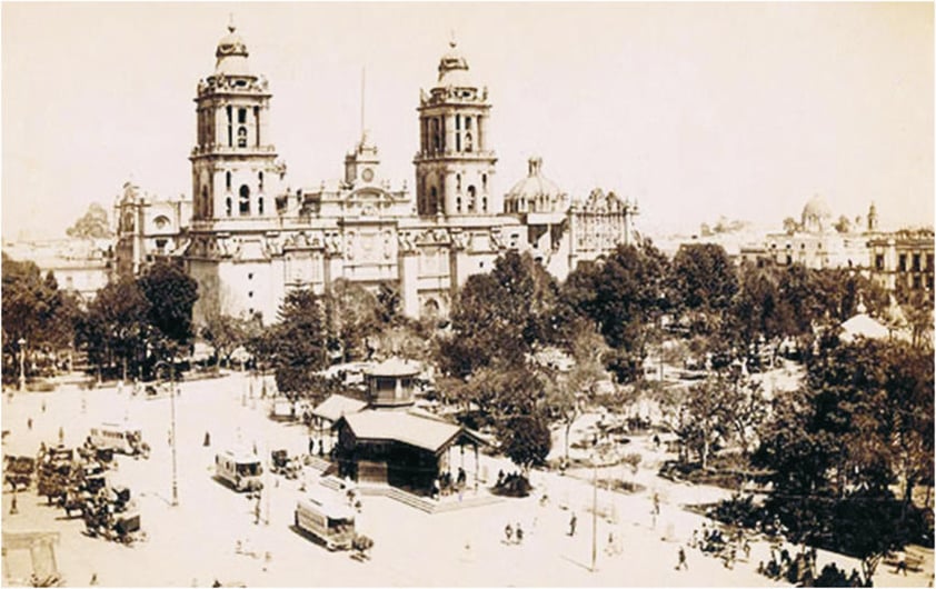 El tranví­a de mulitas, una ordenada y económica forma de viajar durante el porfiriato en la Ciudad de México que duró hasta 1900, año en que Porfirio Dí­az inauguró el sistema de tranví­as eléctricos; aquí­ les vemos en la estación principal en el Zócalo que entonces estaba arbolado, la catedral metropolitana se ubica al fondo.