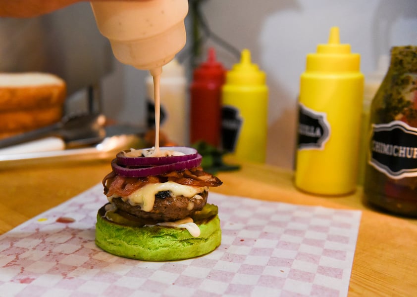 'El pan nosotros lo hacemos de color verde y le ponemos los picos simulando el virus. La carne también la hacemos nosotros y además le agregamos espinacas y un aderezo con aguacate. Les agregamos mayonesa, tomate, pepinillos, queso gouda, queso cheddar, queso mozzarella, tocino, cebolla morada, salsa borboun, catsup y mostaza', detalló.