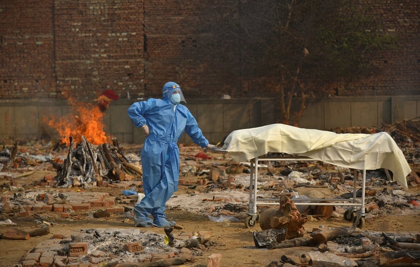 Un familiar vestido con un equipo de protección individual espera para llevar a cabo los últimos rituales de la cremación de un familiar en Nueva Delhi, India, el 29 de abril de 2021.