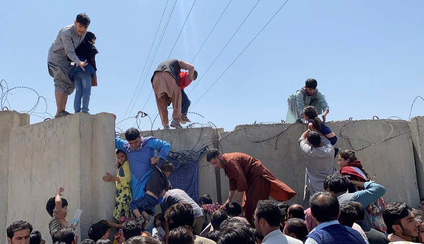 Afganos se agolpan a lo largo del muro del aeropuerto internacional Hamid Karzai en Kabul, Afganistán, el 16 de agosto de 2021, para saltar el muro en un intento de poder abandonar el país después de darse a conocer que el propio presidente, Ashra Ghani había huido después de que los talibanes tomaran control de la capital.