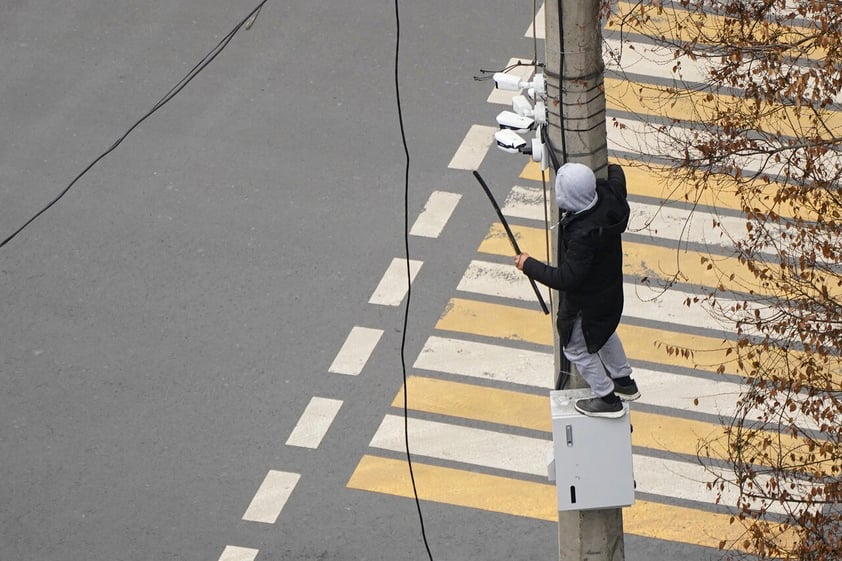 A demonstrator tries to dismantle a security camera on a pole during a protest in Almaty, Kazakhstan, Wednesday, Jan. 5, 2022. Demonstrators denouncing the doubling of prices for liquefied gas have clashed with police in Kazakhstan's largest city and held protests in about a dozen other cities in the country. (AP Photo/Vladimir Tretyakov)