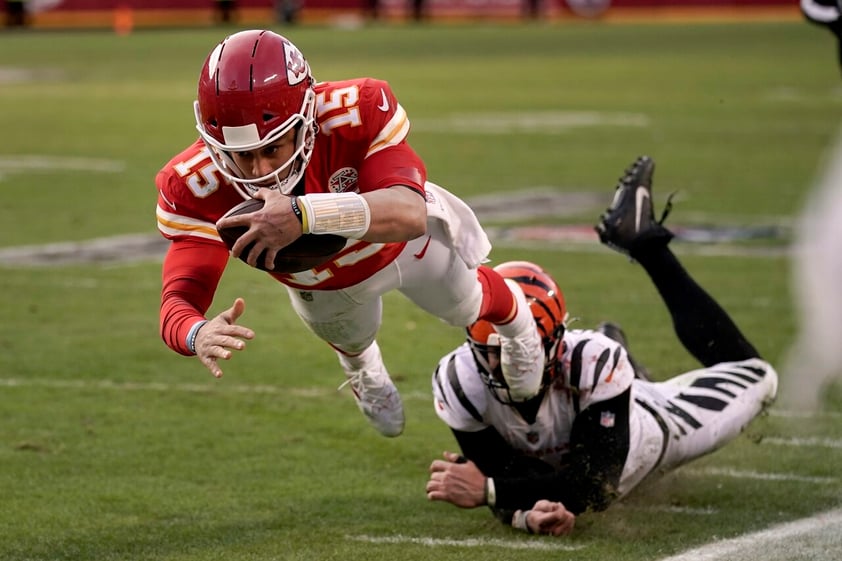 Patrick Mahomes (15), quarterback de Chiefs, se lanza con el balón para escapar de Trey Hendrickson, derecha, de los Bengals de Cincinnati, durante la segunda mitad del juego de campeonato de la AFC, el domingo 30 de enero de 2022, en Kansas City, Mo. (AP Foto/Charlie Riedel)