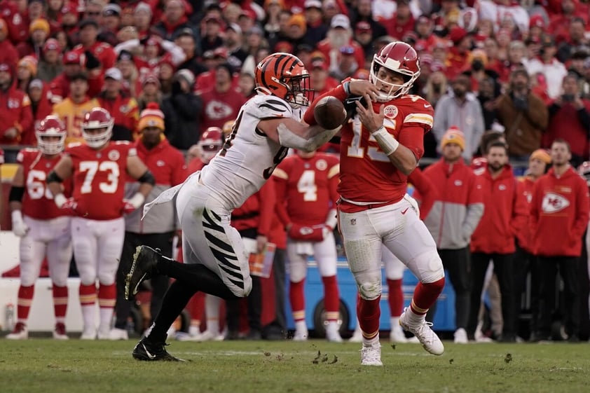 Kansas City Chiefs quarterback Patrick Mahomes (15) fumbles as he is tackled by Cincinnati Bengals defensive end Sam Hubbard, left, during overtime in the AFC championship NFL football game, Sunday, Jan. 30, 2022, in Kansas City, Mo. The Bengals won 27-24. (AP Photo/Charlie Riedel)