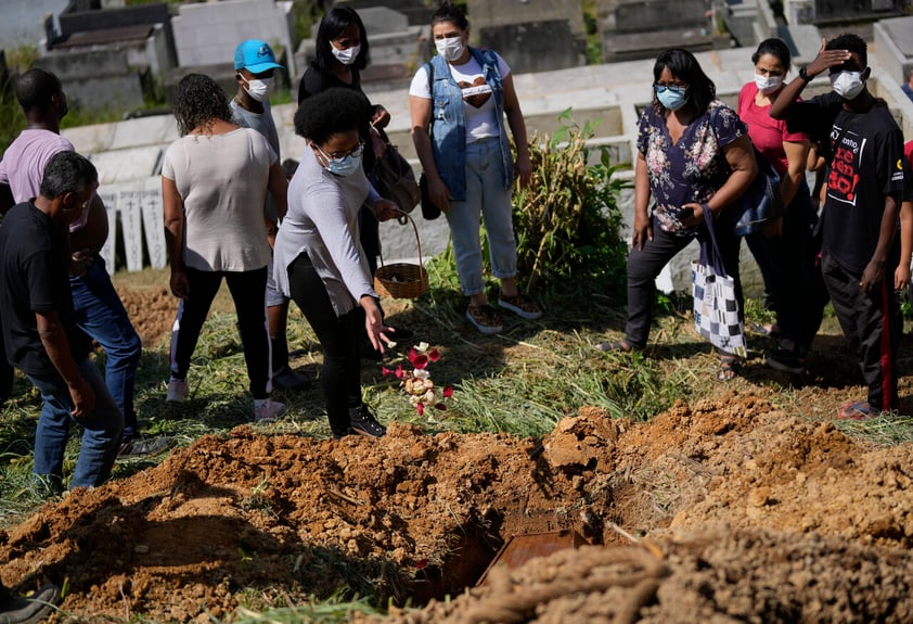 A daughter of 54-year-old woman Zilmar Batista, who died in the mudslides, sprinkles flower petals over her mother's casket at the Municipal cemetery in Petropolis, Brazil, Thursday, Feb. 17, 2022. Deadly floods and mudslides swept away homes and cars, but even as families buried their dead, it was unclear how many bodies remained trapped in the mud. (AP Photo/Silvia Izquierdo)