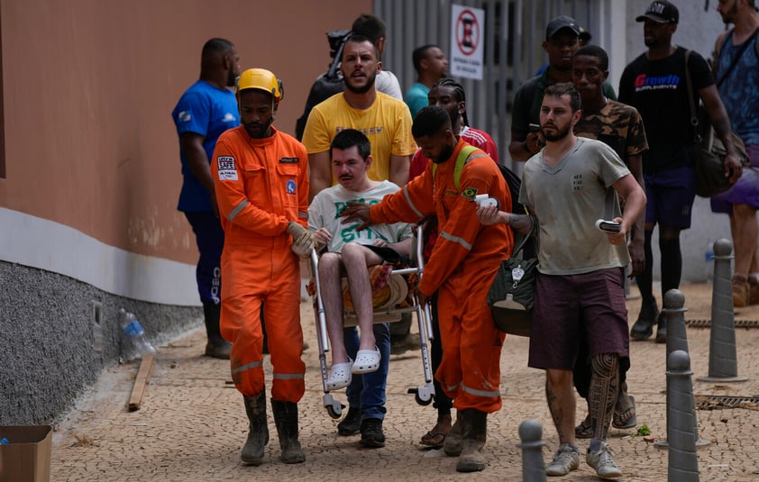 Rescue workers help a resident to evacuate an area under new landslide risk in Petropolis, Brazil, Thursday, Feb. 17, 2022.  Deadly floods and mudslides swept away homes and cars, but even as families prepared to bury their dead, it was unclear how many bodies remained trapped in the mud. (AP Photo/Silvia Izquierdo)