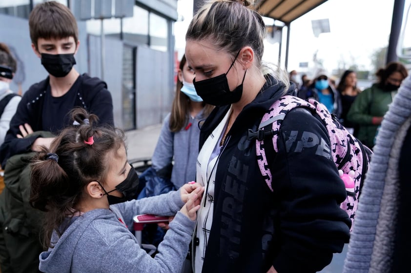 A woman from Ukraine stands with her children before crossing into the United States, Thursday, March 10, 2022, in Tijuana, Mexico. U.S. authorities allowed the woman and her three children to seek asylum Thursday, a reversal from a day earlier when she was denied entry under the Biden administration's sweeping restrictions for seeking humanitarian protections. (AP Photo/Gregory Bull)